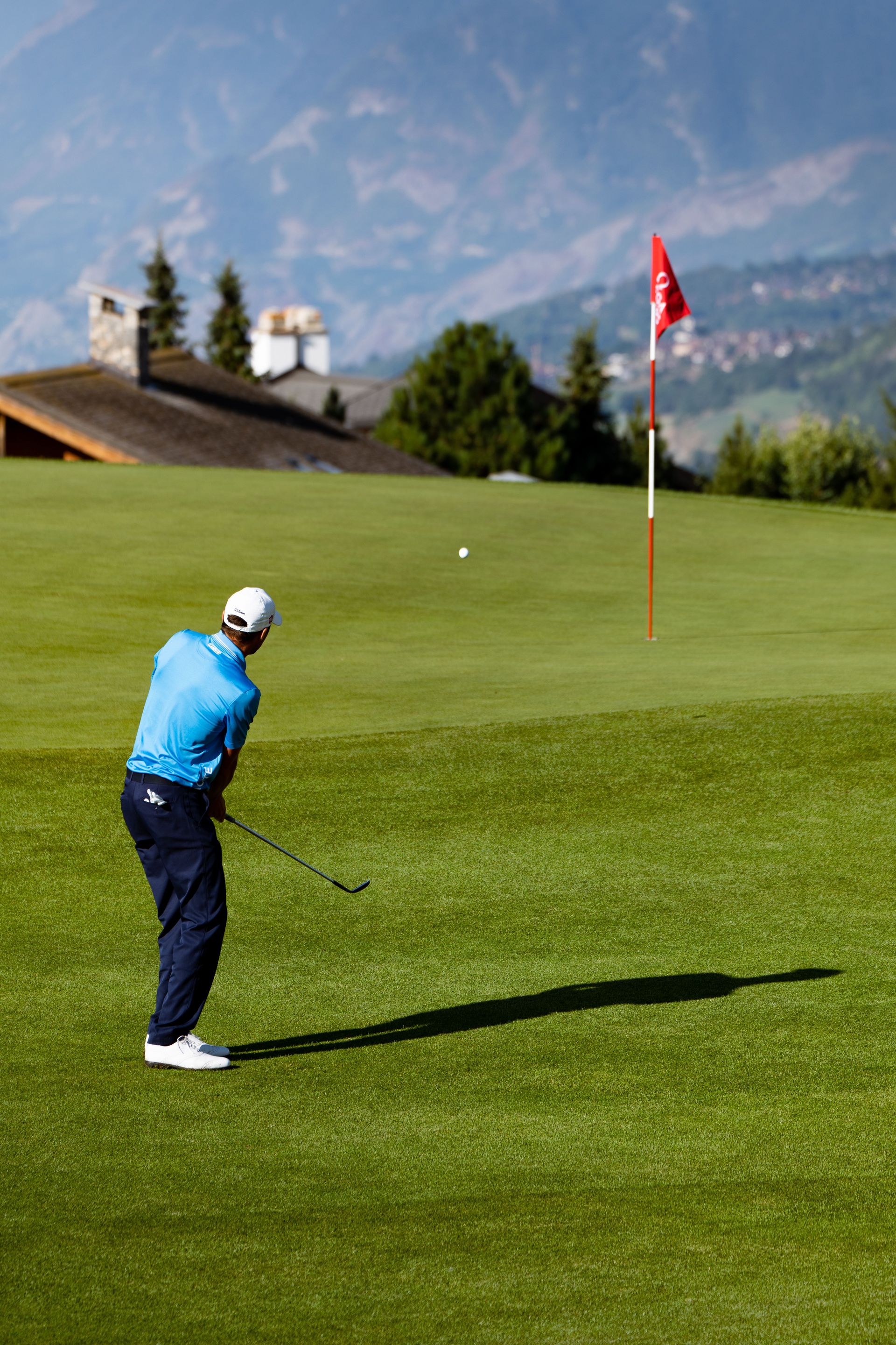 Golfer playing on a picturesque course in Crans-Montana, Switzerland with mountain views.